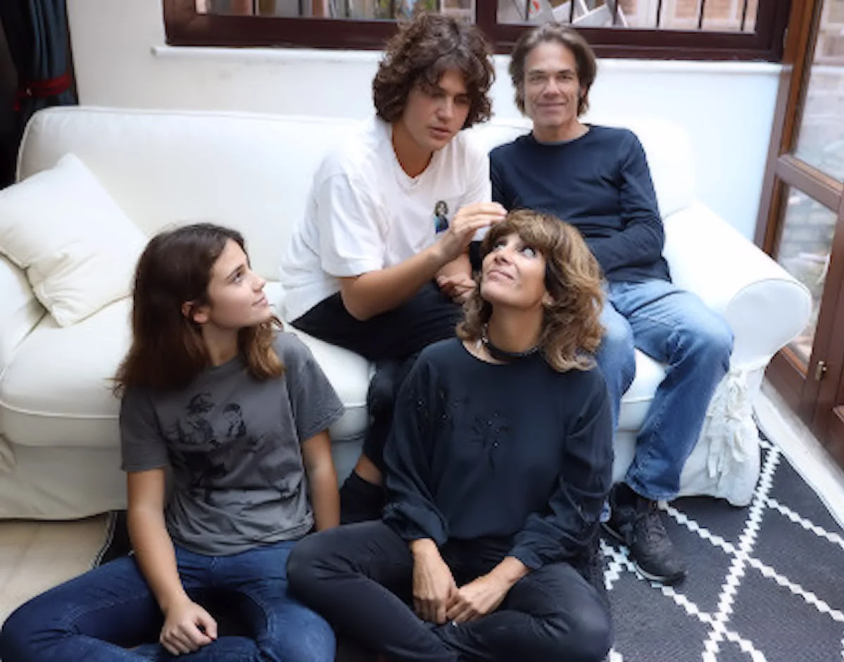 Pablo con il papà Karl, la sorella Gloria e la mamma Alessia, seduti insieme su un divano bianco in casa